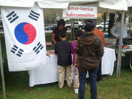 RI Heritage Day Festival에 설치된 한국 부스에 몰려든 어린이들. 옆에 큰 태극기가 걸려 있다.