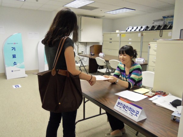 지난 해 6월 재외국민 모의선거에 참여한 유권자가 투표 사무원에게 신분증을 제시해 확인을 받은 후 투표용지를 발급 받는 모습.