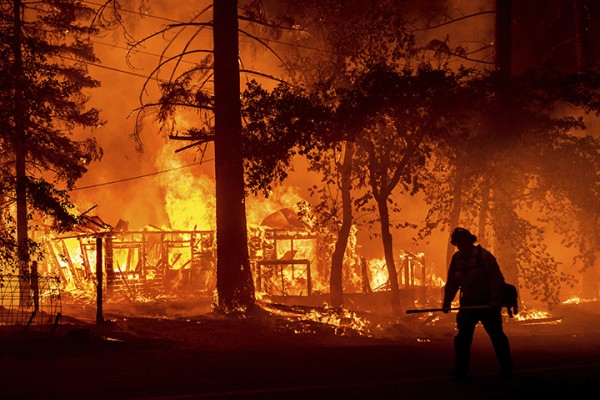 캘리포니아주 플루머스 카운티에서 24일(현지시간) 딕시란 이름의 대형 산불이 주택을 불태우고 있는 화재 현장을 한 소방관이 지나고 있다. 미 서부 13개 주에서는 극심한 가뭄에 폭염이 겹치면서 80여 건의 산불이 발생해 주변으로 번지고 있다.