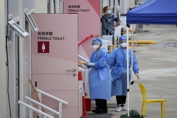2022년 3월 26일 홍콩의 신종 코로나바이러스 감염증(코로나19) 환자 임시 격리시설에서 보호복을 차용한 직원들이 화장실 앞에 서 있다.