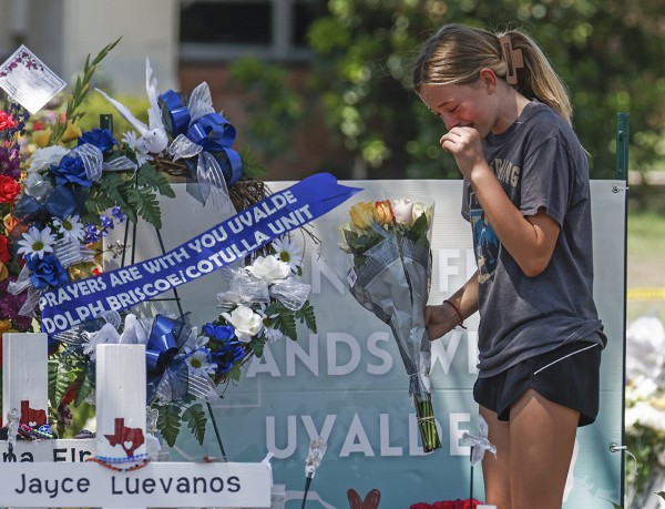 28일 미국 텍사스주 유밸디의 롭 초등학교 총격 희생자 기념비에 헌화한 소녀가 울음을 터뜨리고 있다.