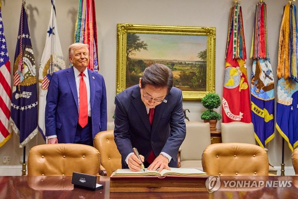 이재명 대통령이 25일(현지시간) 미국 워싱턴 DC 백악관에서 도널드 트럼프 미국 대통령이 지켜보는 가운데 방명록을 작성하고 있다.